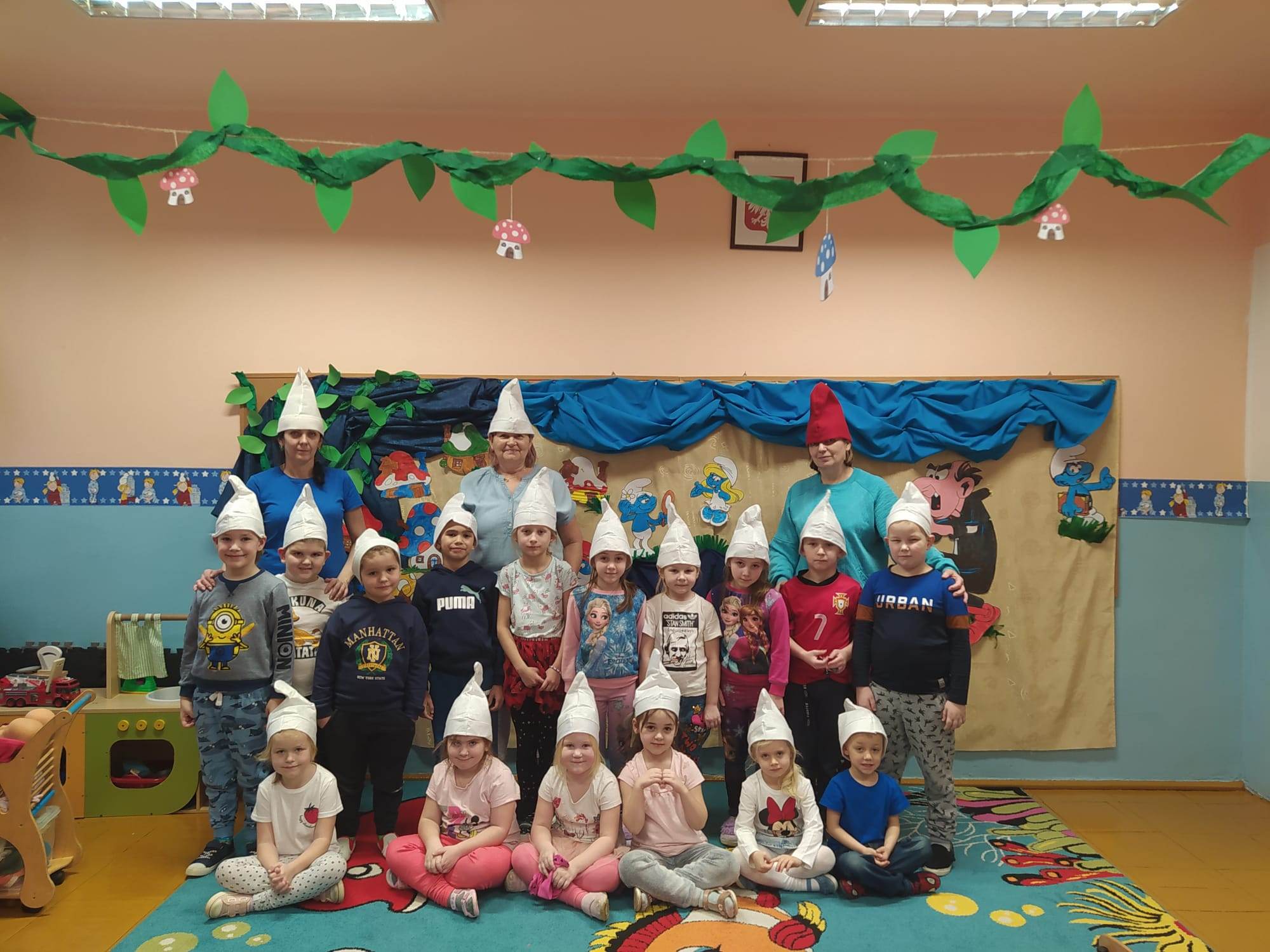 Grupa Kotki pozuje na tle smerfnej wioski